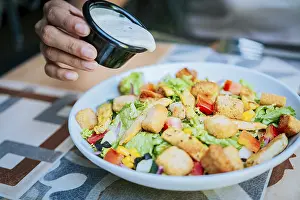 Healthy Food Prints: Hand putting dressing on a caesar salad