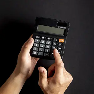 Capital Market Symbolism Prints: Hands using black mini calculator