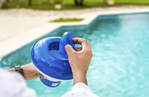 Swimming Pool Disinfection Prints: Hands of a worker installing a pool chlorine float