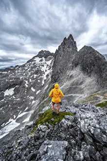 Dramatic Clouds Europe Prints: Hiker looking at mountains under dramatic clouds