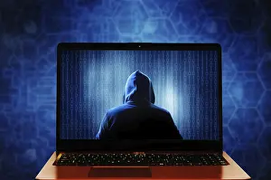 Data Security Protection Prints: A hooded mysterious hacker figure inside a laptop screen displaying binary code