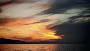 Atmospheric Light Of The Setting Sun Prints: Intense sunset with dramatic cloud formations over water
