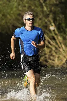 Recreational Activity In Southern Germany Prints: Jogger running through a stream