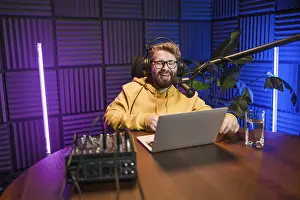 Images Dated 6th February 2024: Print of a Smiling Male Radio Host Reading from a Microphone