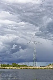 Cloudy Sky Landscape Shot Prints: A large power pole in a vast landscape under dramatic clouds