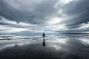 Icelandic Nature Tourism Prints: Lonely hiker on the beach, dramatic clouds