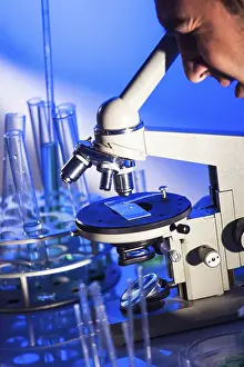 Laboratory Equipment Usage Prints: Man is looking into the ocular of microscope