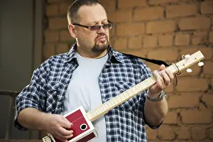 Musician Portrait Prints: Man playing his three string cigar box guitar