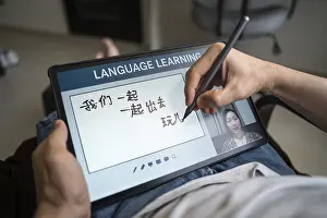 Language Training At Home Prints: A man studies Mandarin at home using a tablet for online language learning