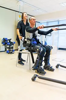 Healthcare Innovation Technology Prints: Mechanical exoskeleton. Female physiotherapy doctor assistant lifting disabled person with robotic skeleton to get up