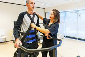 Physical Disability Support Prints: Mechanical exoskeleton. Female physiotherapy medical assistant with disabled person lifted with robotic skeleton