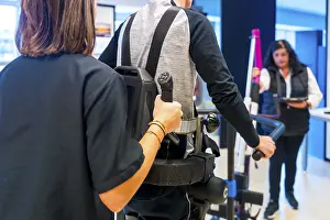 Physical Therapy Exercises Prints: Mechanical exoskeleton. Female physiotherapy medical assistant helping disabled person with robotic skeleton to walk