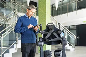 Modern Hospital Technology Prints: Mechanical exoskeleton computer engineer looking at the robot with a tablet