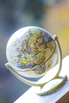 Travel Photography Prints: Miniature globe model standing on a stack of books