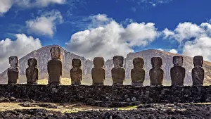Moai Statues Prints: Moai statues against a mountain backdrop and dramatic sky with clouds