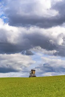 Cloudy Landscape Prints: Mobile raised hide in an empty field under dramatic clouds
