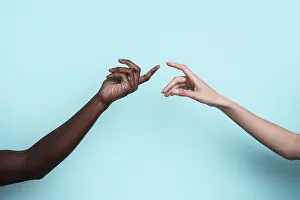 Diversity And Inclusion Prints: Two multiethnic hands reach toward each other against a solid blue backdrop