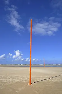 Blue Sky Coastal Scene Prints: Orange-red marker posts on the beach
