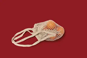 Single Colored Background Photo Prints: Oranges in a string bag on ruby red background