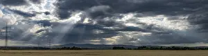 Cloudy Weather Forecast Prints: Panorama of a dramatic sky with sunbeams and fields in the foreground
