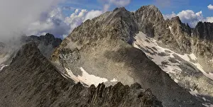 Rugged Mountain Landscape Prints: A panoramic view of a rugged mountain range partially covered by clouds
