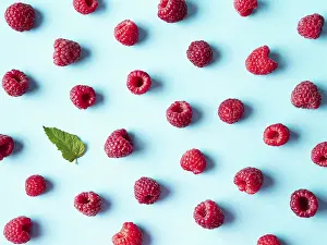 Flat Lay Fruit Photography Prints: Pattern of ripe red raspberry on blue background
