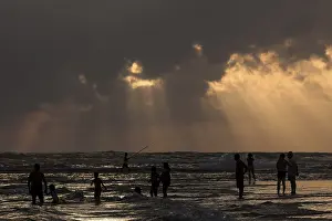 Cloudy Day At The Sea Prints: People in backlight on beach, rays of sunlight
