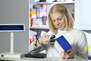 Female Pharmacist At Work Prints: Pharmacist scanning medicine with barcode reader