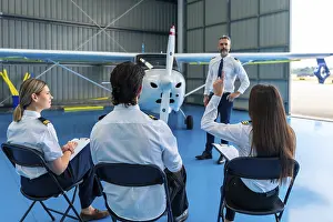 Aviation Education Prints: Pilot instructor explaining aviation concepts to students in a hangar