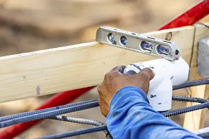 Construction Site Work Prints: Plumber using level while installing PVC pipe at construction site