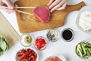 Prints of The process of preparing sushi, preparing all the ingredients for sushi, the girl is holding tuna with chopsticks Tuna Prints: The Process of Preparing Sushi Print