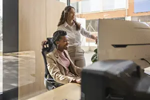 Workplace Collaboration Prints: Two professionals are engaged at a computer in a bright office