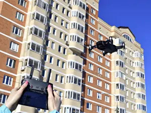 Unmanned Aerial Vehicle UAS Prints: Quadrocopter flies in the sky and hands with a control panel