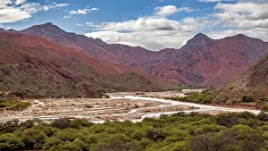 Colorful Rock Formations Prints: River flows through red mountains with clouds in the sky