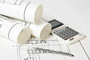 Construction Project Planning Prints: Rolled technical drawings and a calculator
