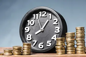 High Resolution Images Prints: Round alarm clock with stack increasing coins against blue background