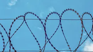 Blue Sky Background Prints: Rusty barbed wire on blue sky background