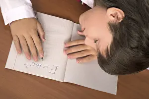 Young Boy Resting Prints: Schoolboy sleeping on the table with notebook