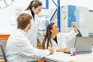 Healthcare Professionals At Work Prints: Scientists looking at samples while working with laptop sitting on a table in a lab