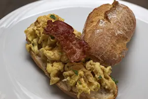 Close Up Scrambled Eggs Prints: Scrambled eggs with fried bacon on a rustic roll