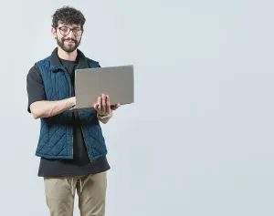 Young Man With Laptop Prints: Smiling Bearded guy using laptop and looking at camera isolated