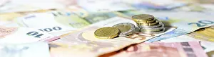 Economic Crisis Image Prints: Stack of coins on euro banknotes as wide panoramic format