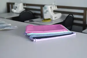Woman Working Prints: A stack of colorful fabrics on a table in a sewing workshop
