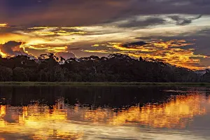 Cloudy Evening Sky Photography Prints: Sunset over a river with dramatic sky and intense reflections