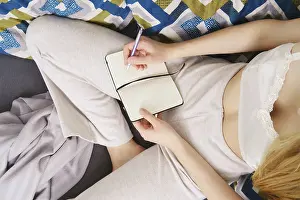 View From Above Concept Image Prints: Taking notes in a notebook sitting at home on the couch (view from above)