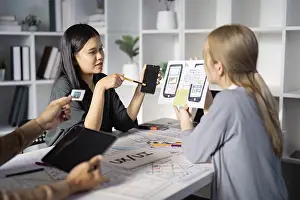Digital Communication Prints: A team of designers discussing mobile app prototypes