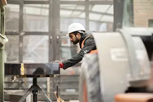 Young Technician In Workshop Prints: Technician with beard and helmet works in a workshop