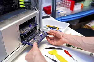 Quality Assurance Process Prints: Technician opening the back part of a computer to repair it in a workshop