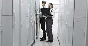 Healthcare Technology Prints: Technicians using laptop while analyzing server in server room