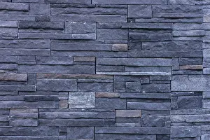 Urban Building Exterior View Prints: A textured wall made of dark stone bricks arranged in a pattern